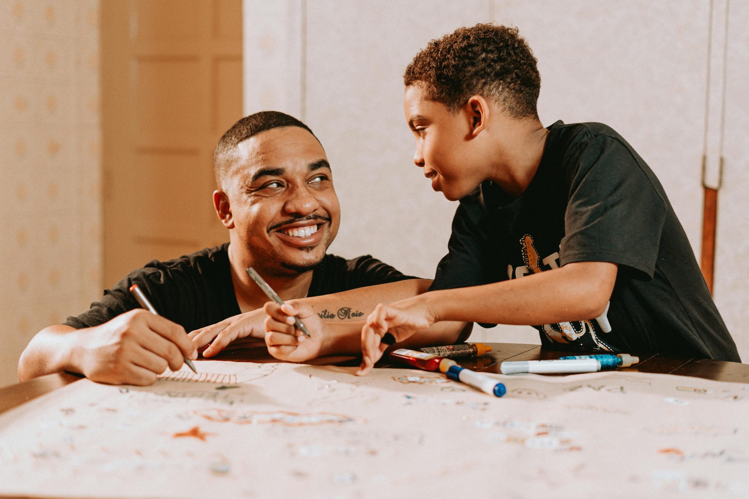 Father and son at a table writing a letter, happy